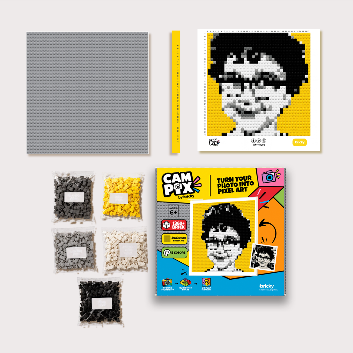 Bricky Cam Pix kit with printed guide, ruler, five color brick packs, and mosaic board for building custom photo pixel art.