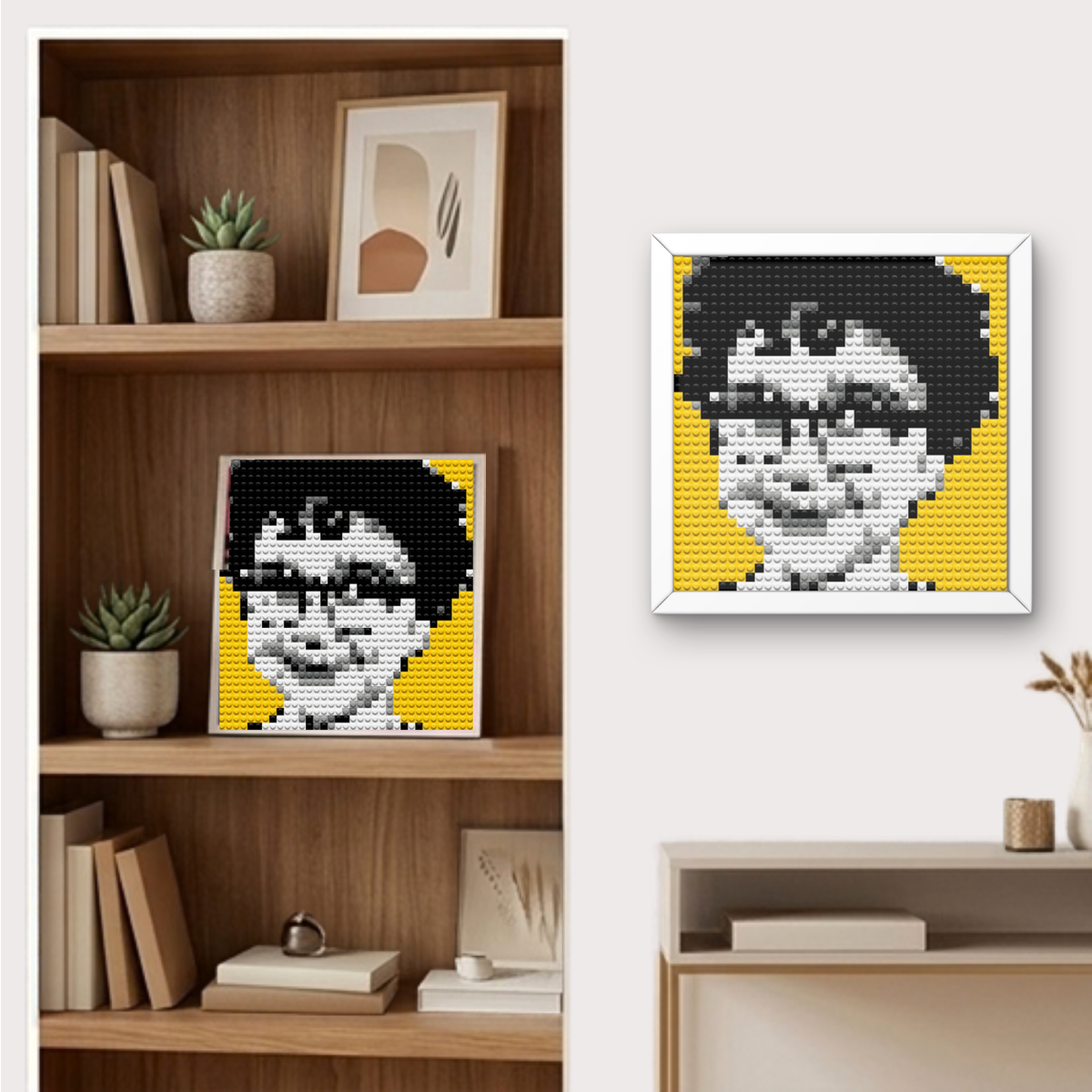 Finished Bricky Cam Pix boy hero pixel art mosaic framed and hanging on a wall and displayed on a shelf. A framed pixel-art portrait of a person with black hair, glasses, and a yellow background, shown hanging on a white wall beside a wooden shelf with books and small plants.